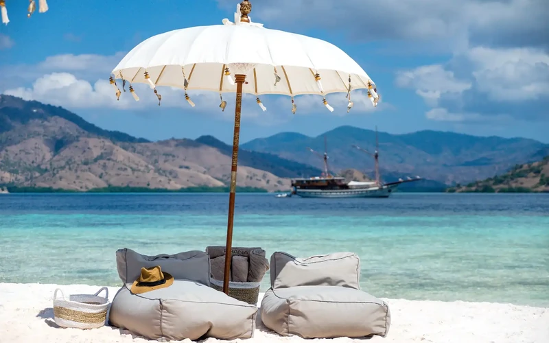Beach setup with a parasol and cushions on white sand