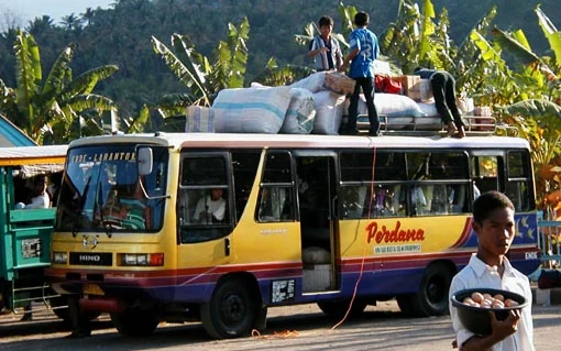 Public bus on a Flores road with cargo loaded on the roof